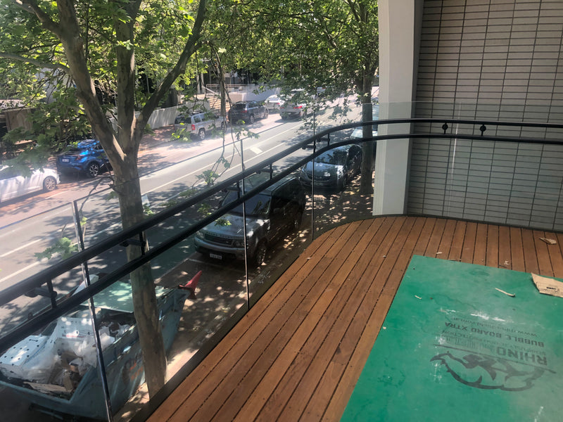 Curved glass railing using a custom extruded base rail for a commercial exterior deck. 